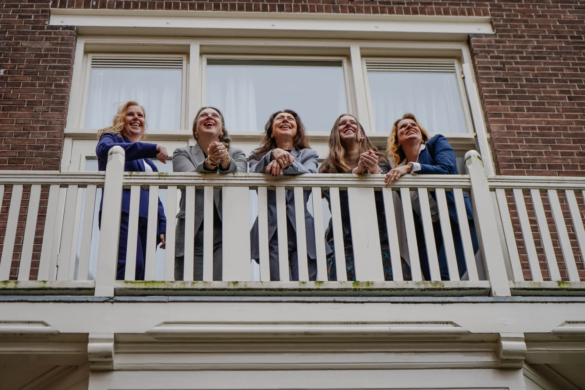 Five staff members look down from the office balcony