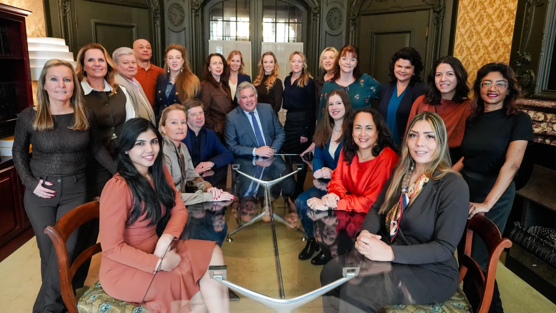 Groepsfoto van het team van Ellens & Lentze rond een tafel in een klassieke kamer