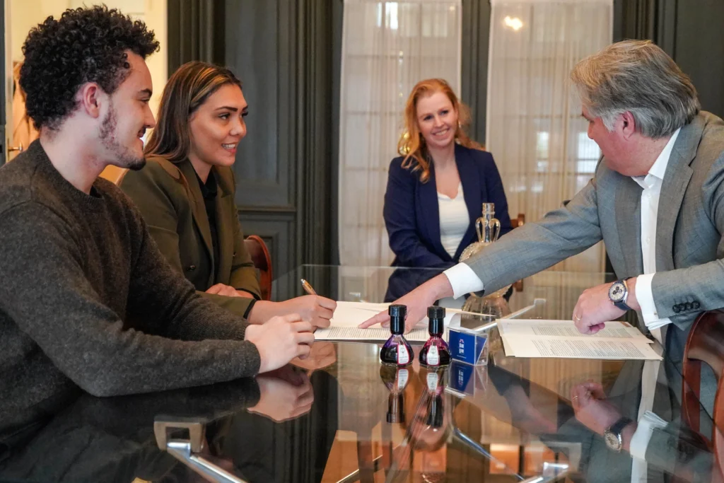 Cliënten en medewerkers aan een glazen tafel tijdens het ondertekenen van documenten