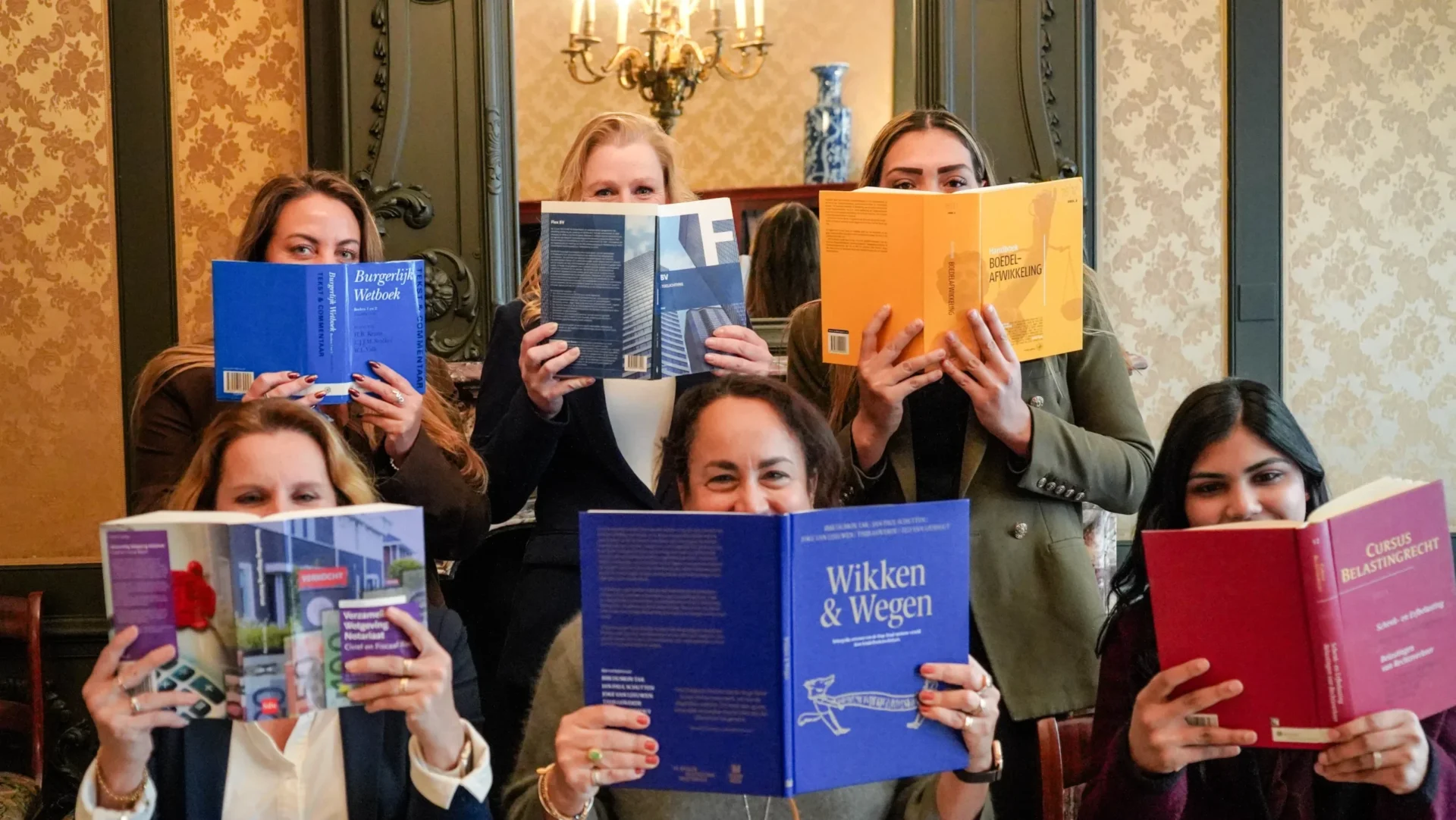 Medewerkers houden opengeslagen juridische boeken voor hun gezicht in een klassieke kamer